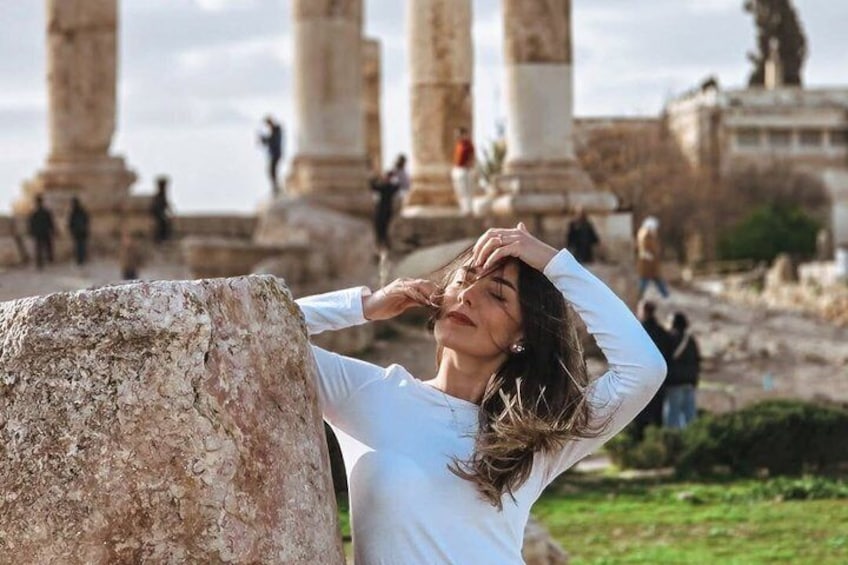 A person leaning on a stone pillar with ancient columns in the background. 2