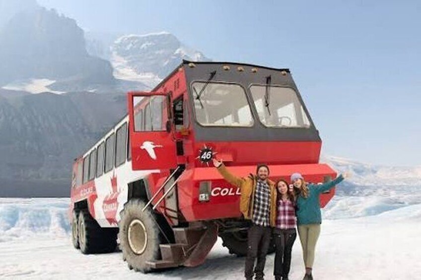 A red and white bus with 'COLL' on the side parked on snow, with mountains in the background. 3
