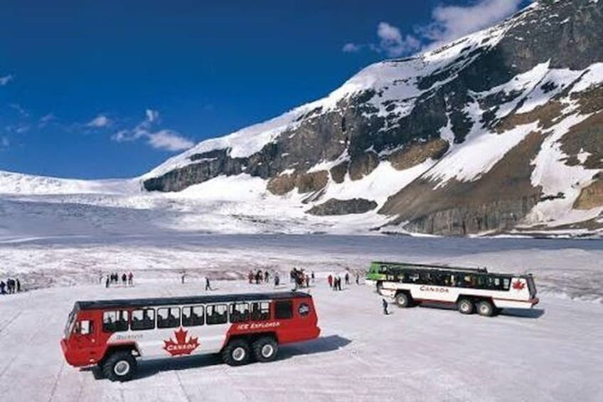 A red and white bus on a snow-covered landscape with mountains in the background. 2