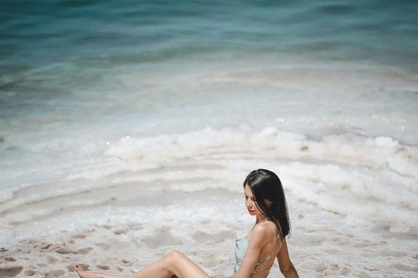 A person sitting on a beach with waves in the background. 3
