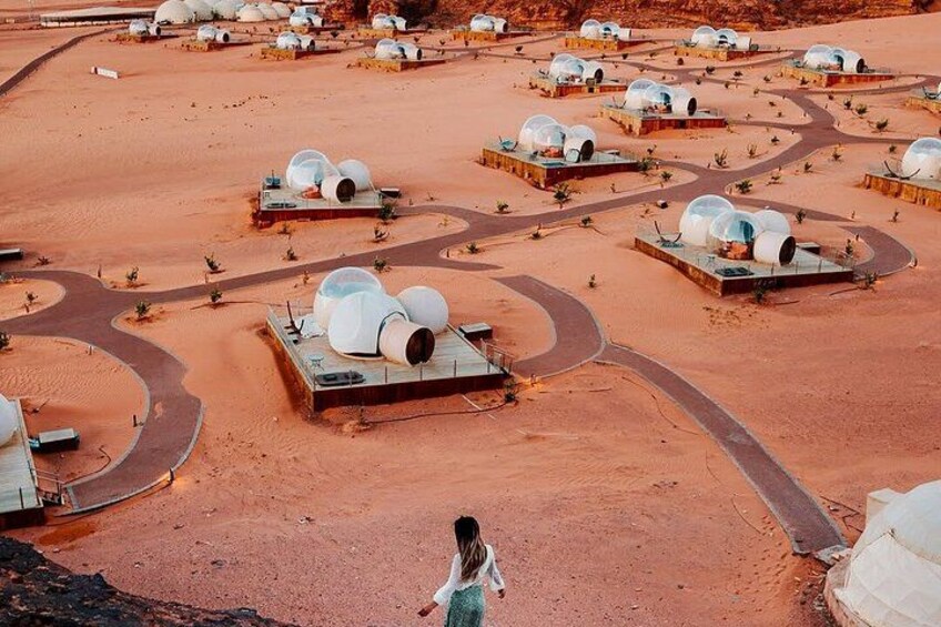 A desert landscape with spherical structures on platforms, arranged in a pattern with winding roads. 2