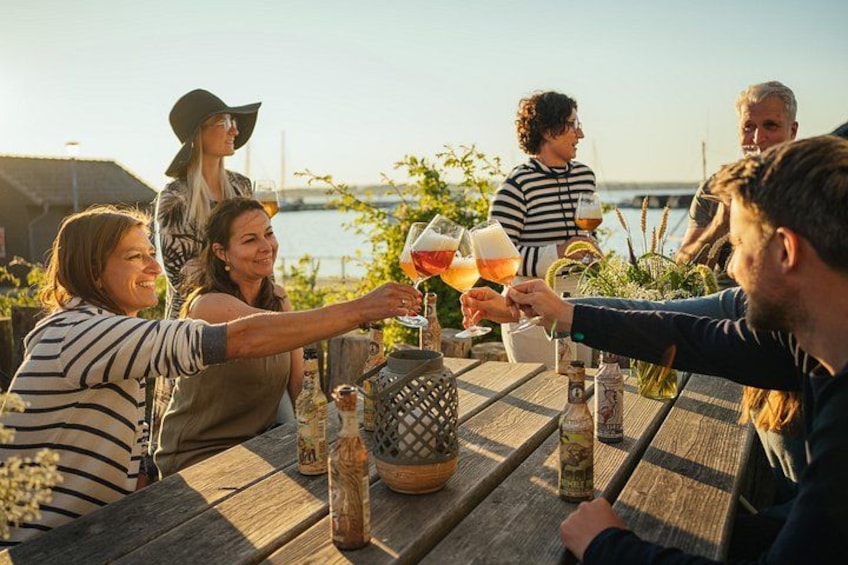 Un grupo de personas brindando con bebidas en una mesa de madera con botellas y vasos. 4