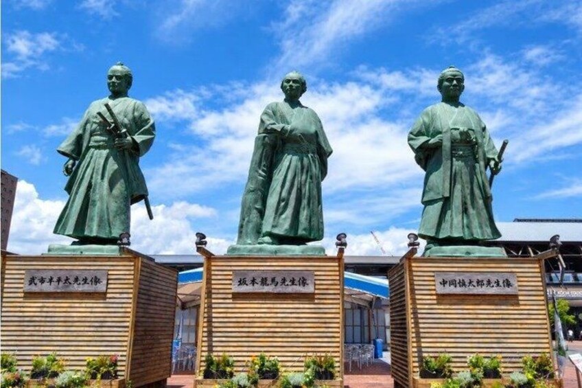 Three bronze statues of historical figures on pedestals with inscriptions. 1