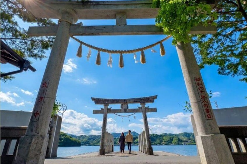 A traditional Japanese torii gate leading to a body of water with mountains in the background. 4
