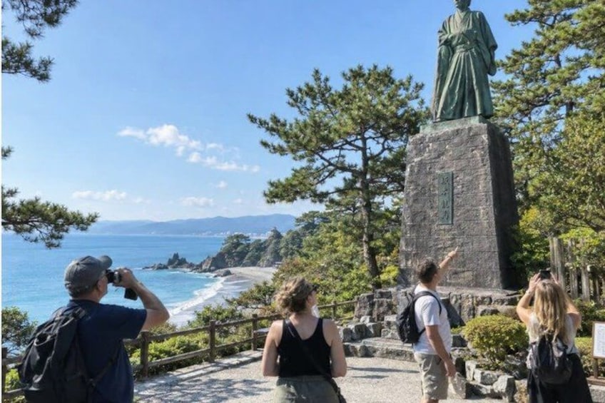 A statue, a coastal view, and a group of people. 5