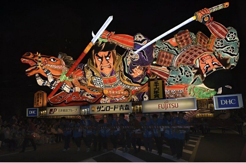A large illuminated display of a samurai warrior with a sword, surrounded by traditional Japanese elements and the text 'FUJITSU' and 'DHC'. 4