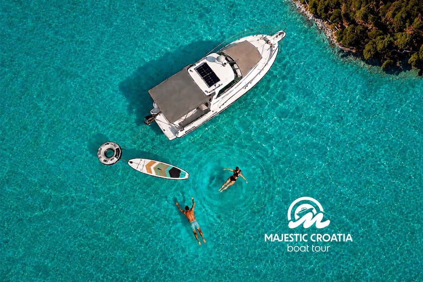 A boat tour in Majestic Croatia with clear turquoise waters and a small boat anchored nearby. 1