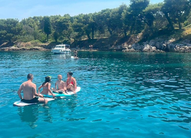A group of people on a boat in a clear blue sea with rocky shores and trees in the background. 3