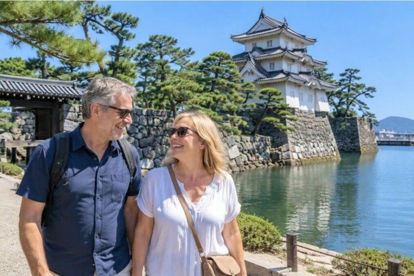 A couple standing in front of a traditional Japanese castle by a body of water. 3