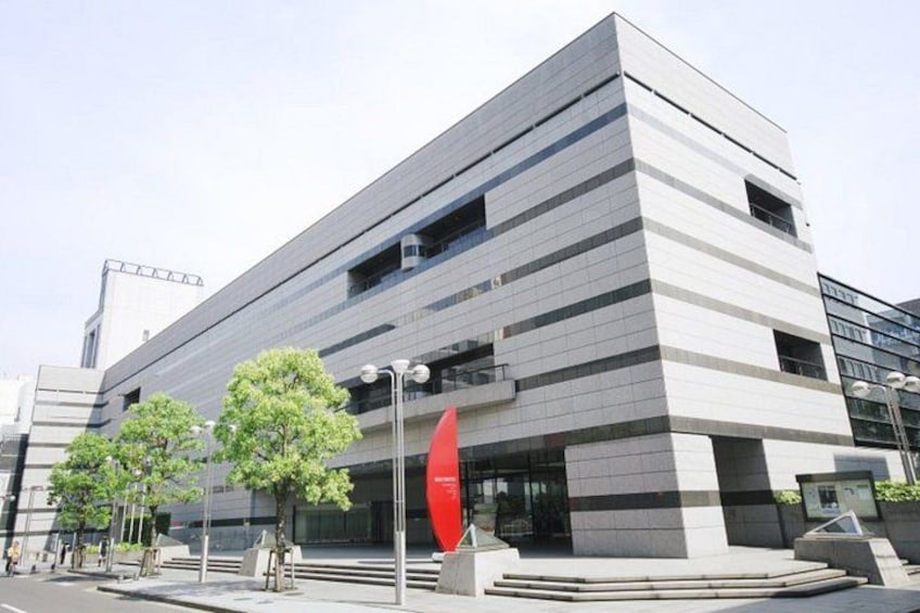 A modern building with a flat roof, large windows, and a red circular sign. 2
