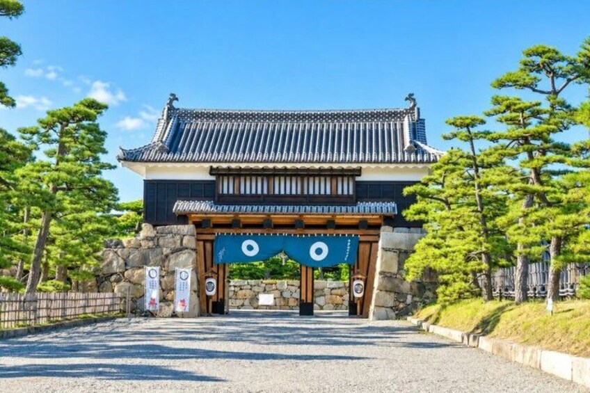 A traditional Japanese gate with a tiled roof and wooden beams, surrounded by pine trees. 4