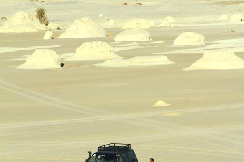 A desert landscape with sand mounds and a vehicle in the foreground. 2