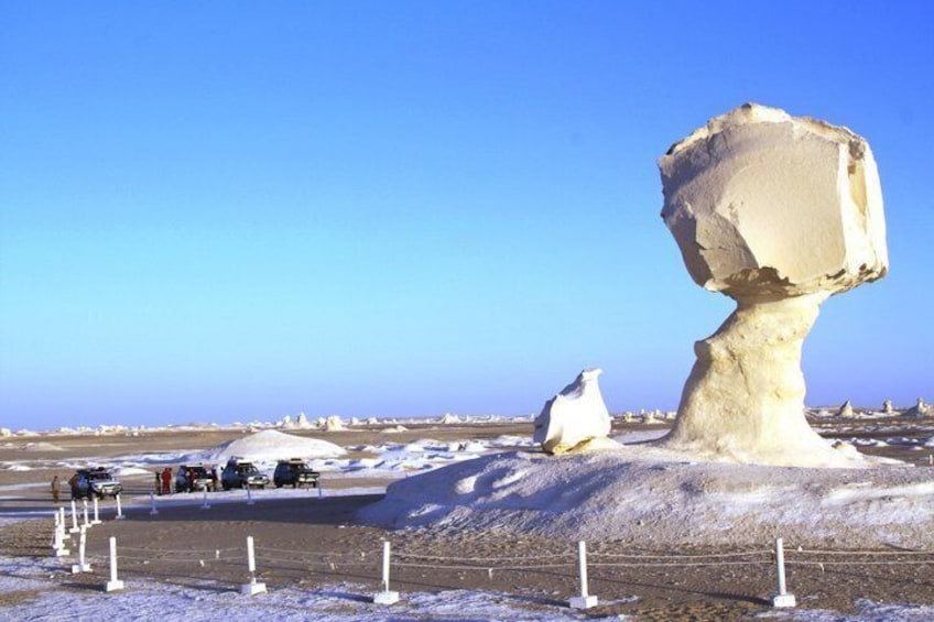 A large rock formation in a snowy landscape with several smaller rocks and a clear blue sky. 5
