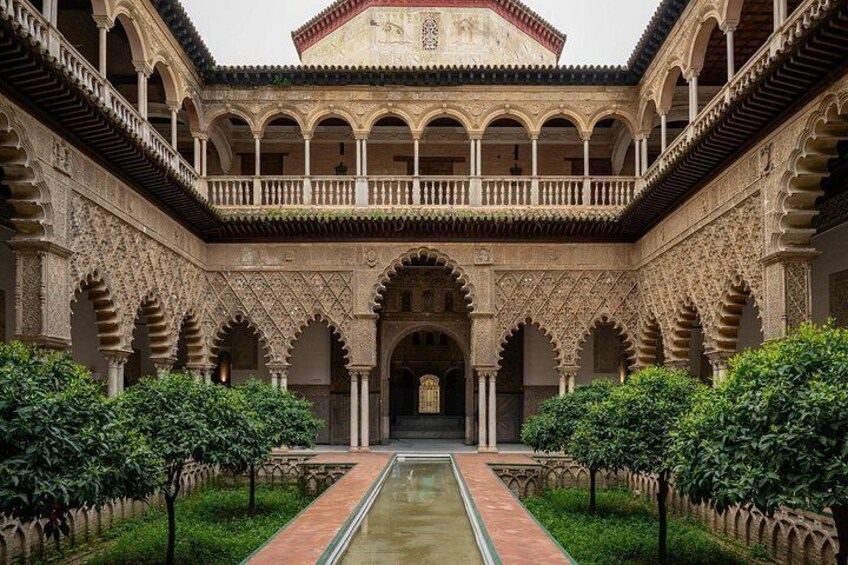 Un patio con arcos, un canal central de agua y un edificio con fachada detallada. 2
