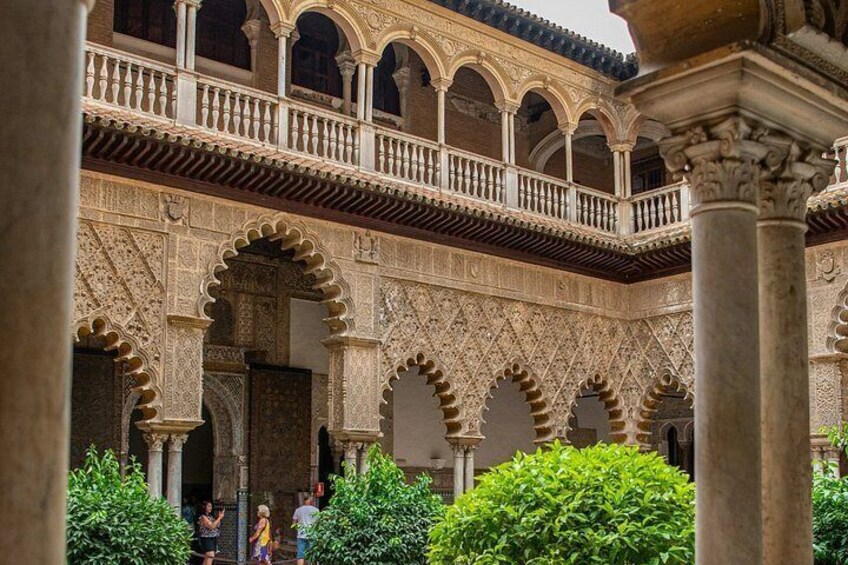 Un patio con arcos, columnas y un balcón. 1