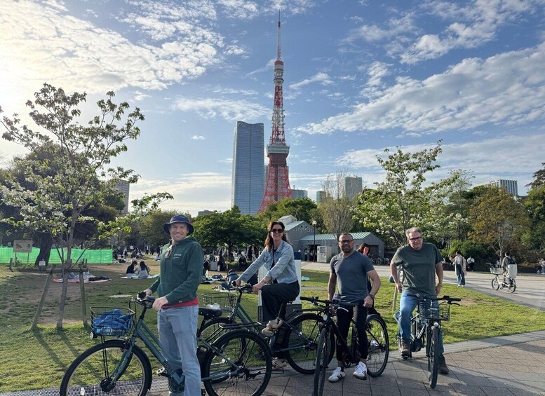 A group of people with bicycles in a park with a city skyline in the background. 1