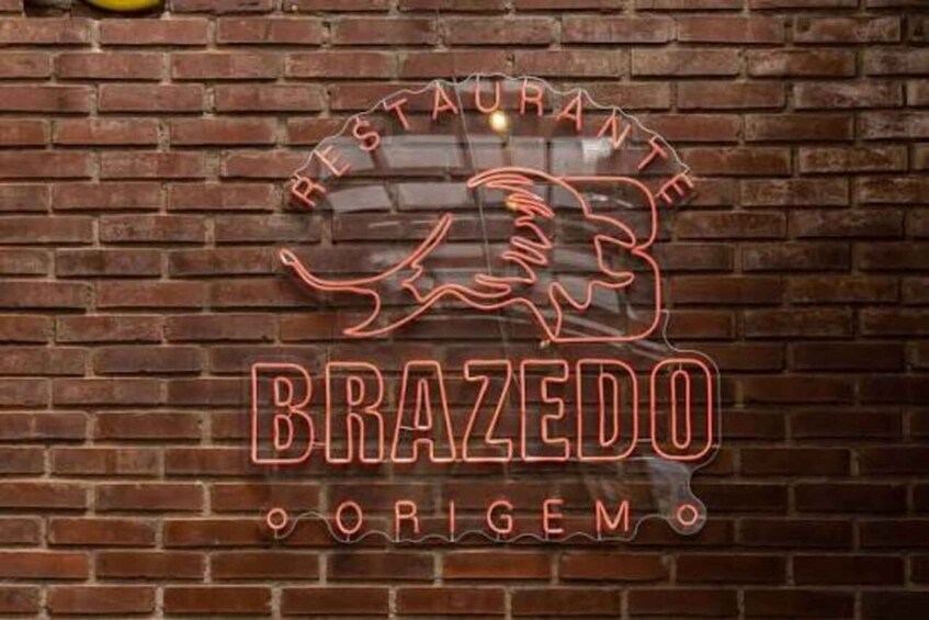 A neon sign on a brick wall with the words 'RESTAURANTE BRAZEDO ORIGEM' and a stylized lion's head. 2