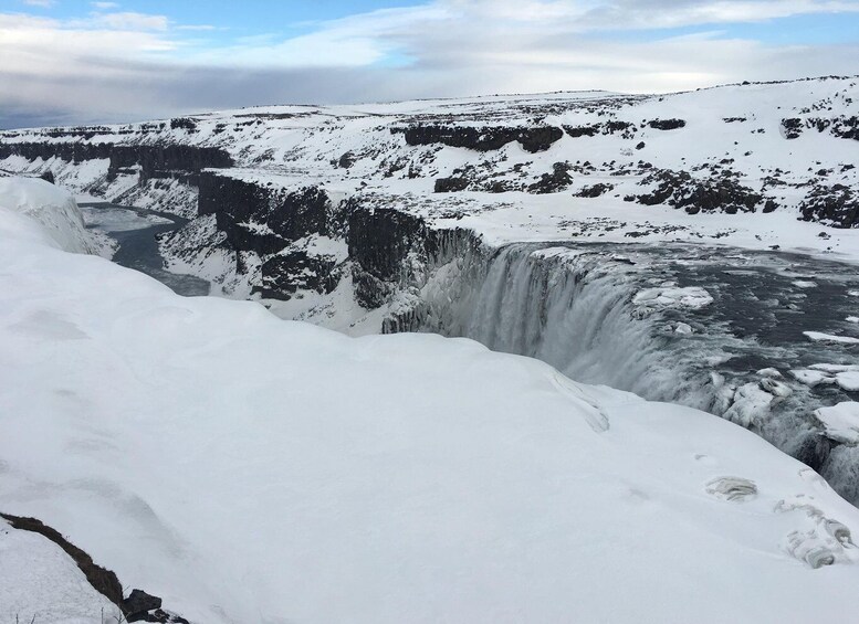 A snow-covered waterfall with a river below, surrounded by snow-covered hills. 3