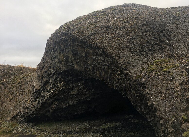 A large, rugged rock formation with a natural archway. 1