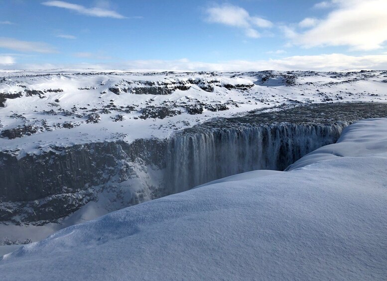 A snowy waterfall cascading over a rocky cliff. 2
