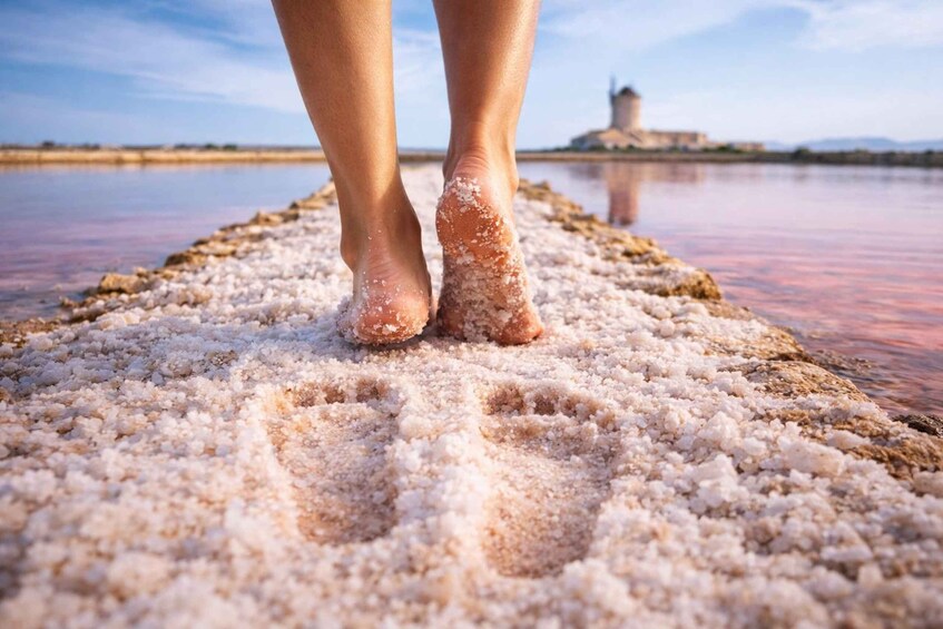 A pair of feet standing on salt flats with a distant tower. 2