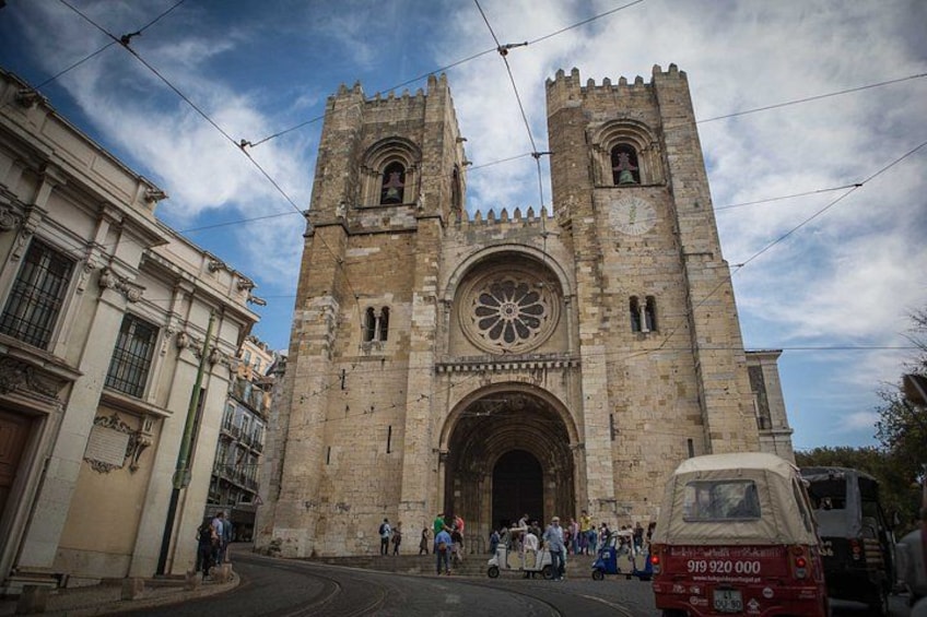 A historic cathedral with two towers, a large rose window, and a street with people and vehicles. 5
