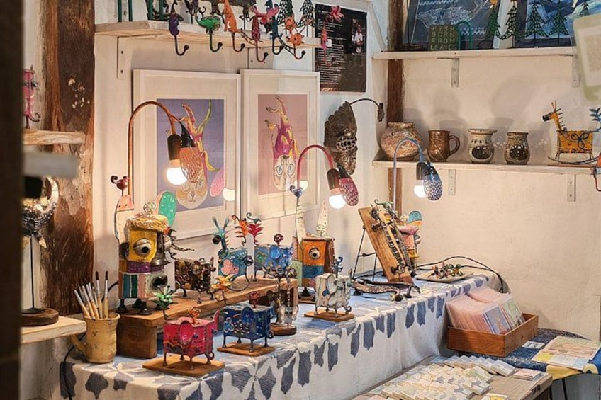Une table encombrée, ornée de divers objets décoratifs, notamment des lampes, des figurines et des pièces de poterie. 3