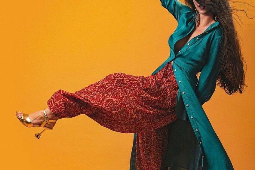A person in a teal shirt and red patterned pants against an orange background. 2