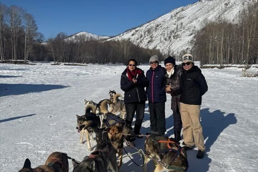 A group of people with sled dogs in a snowy landscape with mountains in the background. 2
