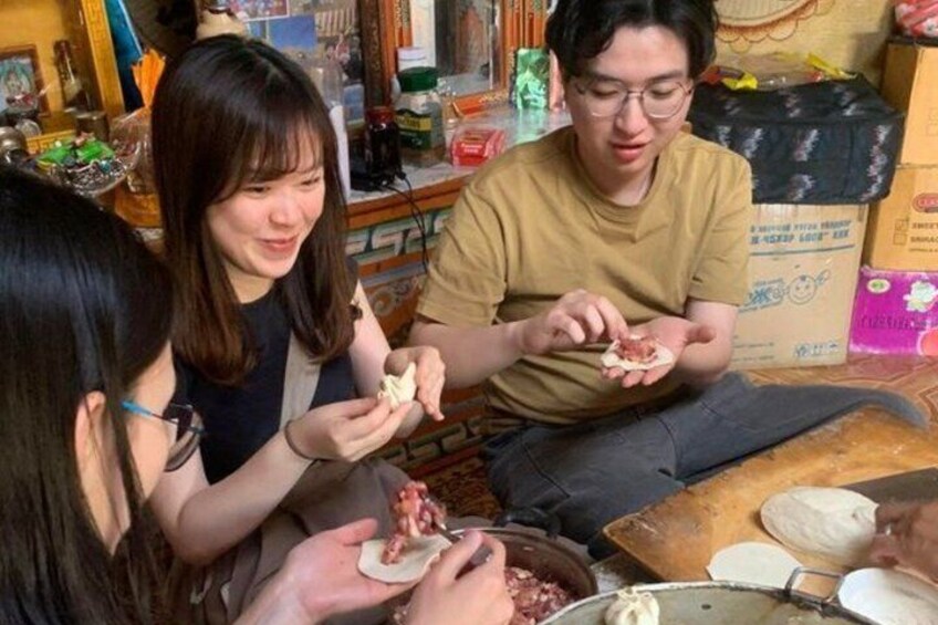 Three people sitting on the floor, preparing food with ingredients and utensils. 3