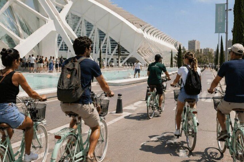 Folk cykler på en gade i byen, med en moderne bygning i baggrunden. 4