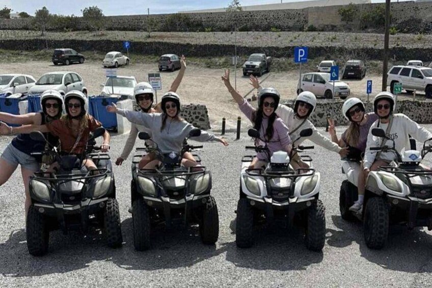 A group of people on ATVs in a parking lot with cars and a stone wall in the background. 5