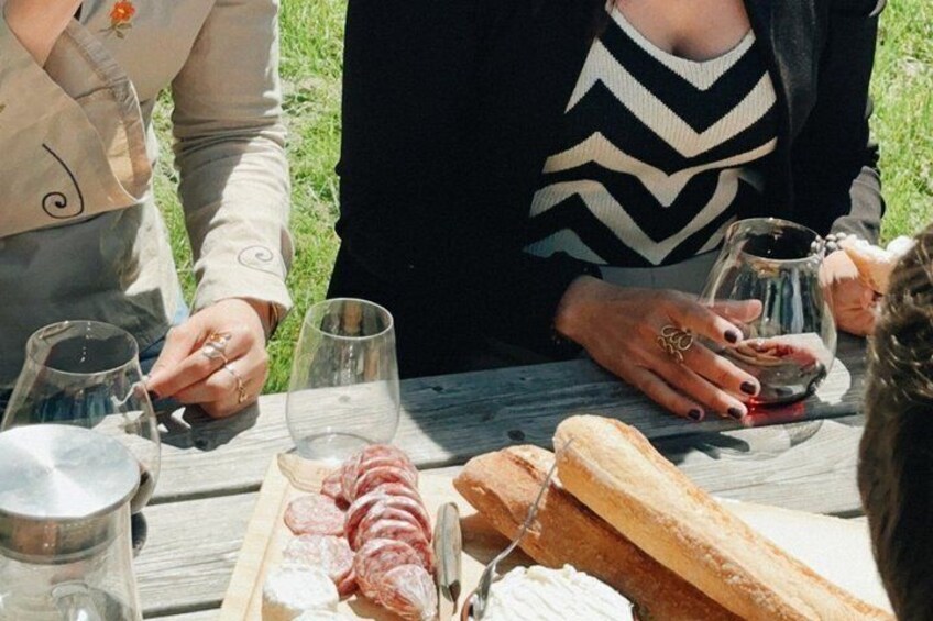 A picnic with food and wine glasses on a wooden table. 4