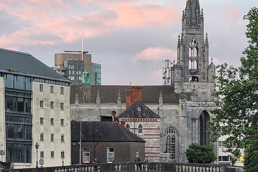 A historic church with a tall bell tower, a modern building, and a bridge. 3