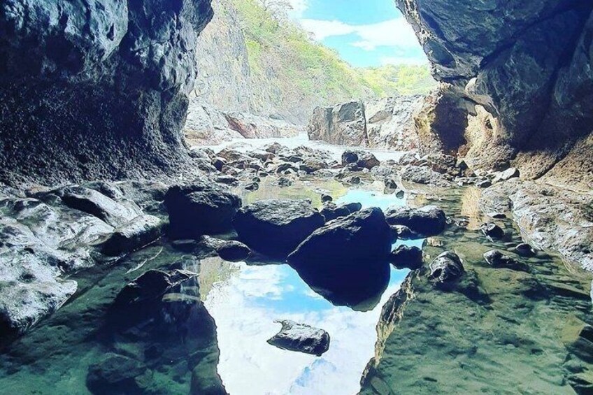 Un arroyo pedregoso con agua cristalina, rodeado de grandes rocas y acantilados. 2