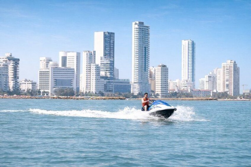 Eine Person fährt mit einem Jetski auf dem Wasser, im Hintergrund ist eine Stadtlandschaft zu sehen. 4