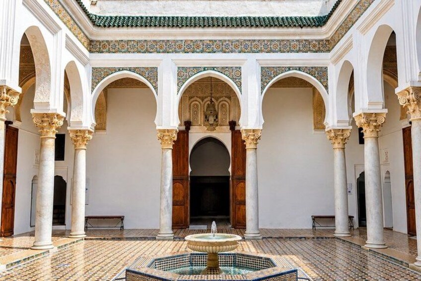 Un cortile interno con archi, colonne e una fontana. 5