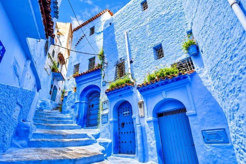 Un vicolo stretto con edifici dipinti di blu, una scala e una porta blu. 3