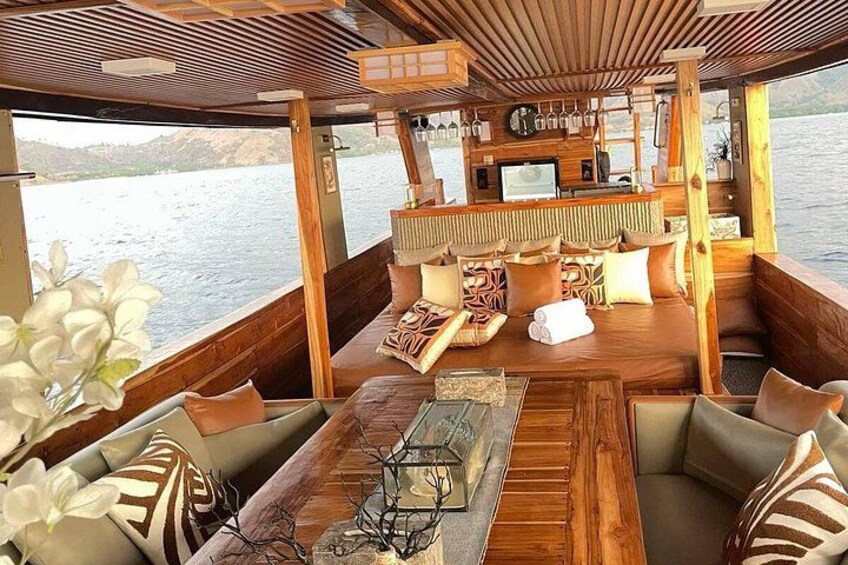 A wooden boat interior with seating, a bar area, and a view of the water. 1