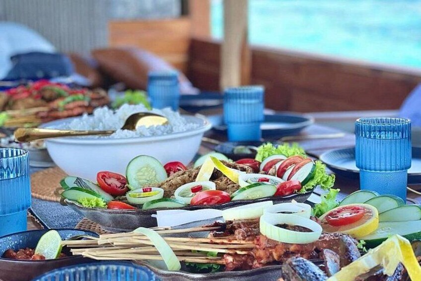 A table with various dishes, including skewered meats, vegetables, and a bowl of rice. 3