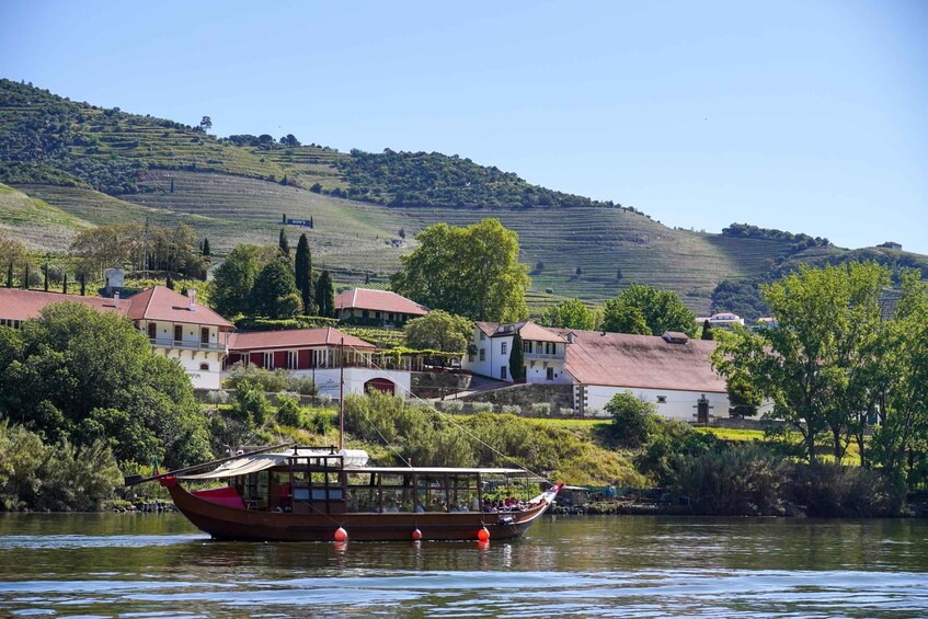 A boat on a river with houses and hills in the background. 3