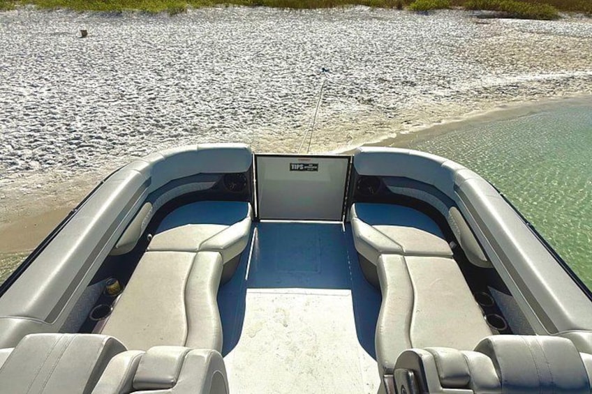 Un bateau avec deux sièges et un volant, amarré sur une plage de sable fin, dans une eau cristalline. 2