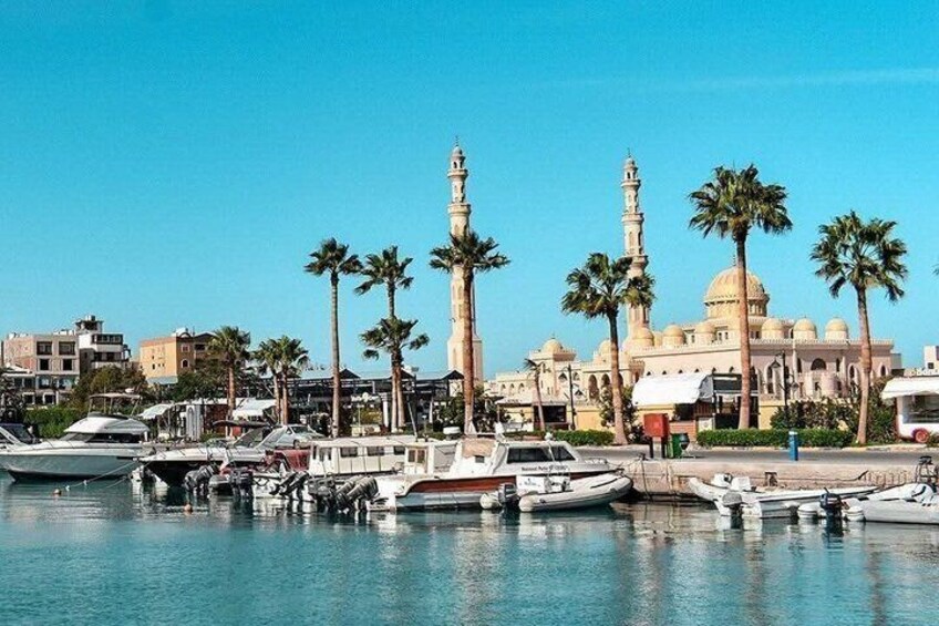 Un port de plaisance avec des bateaux, des palmiers et une mosquée dotée d’un minaret. 5