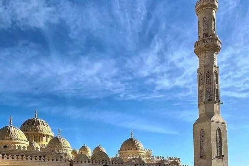 Une mosquée dotée de plusieurs dômes et d’un minaret imposant, le tout sous un ciel bleu dégagé. 3