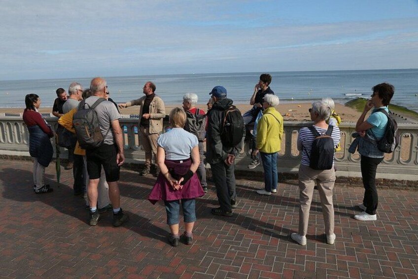 A group of people standing on a brick-paved walkway overlooking the sea. 5