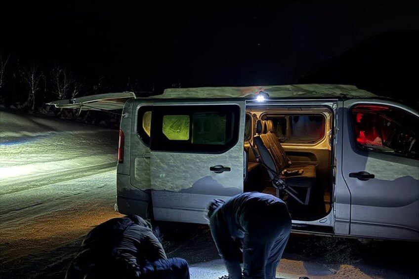 Een busje geparkeerd aan de kant van de weg in de nacht, met de achterklep open, waardoor het interieur zichtbaar is. 2