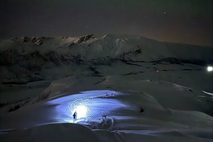 Een besneeerd landschap 's nachts, met een persoon in een lichtcirkel. 4