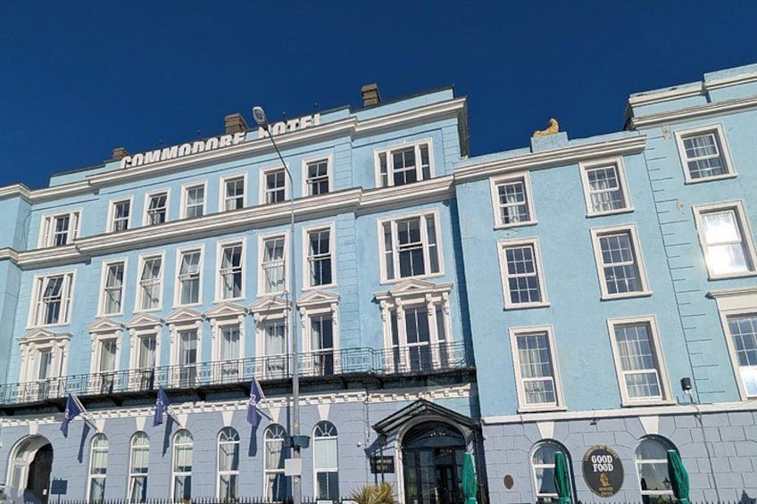 Un edificio azul con el letrero 'COMMONWEALTH HOTEL' y un anuncio que dice 'GOOD FOOD'. 5