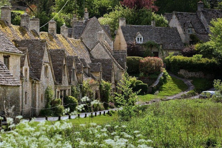 A village with stone houses, a grassy hill, and a winding path. 5