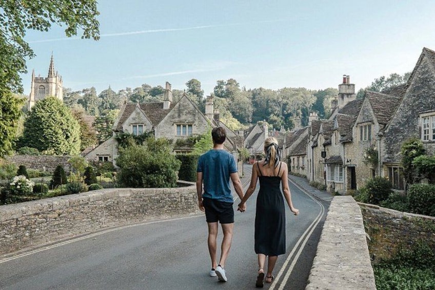 A couple walking down a narrow road flanked by stone walls and traditional houses. 2